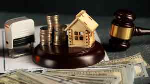 Wooden house model on gavel with coins and cash, symbolizing tax resolution and IRS liens.