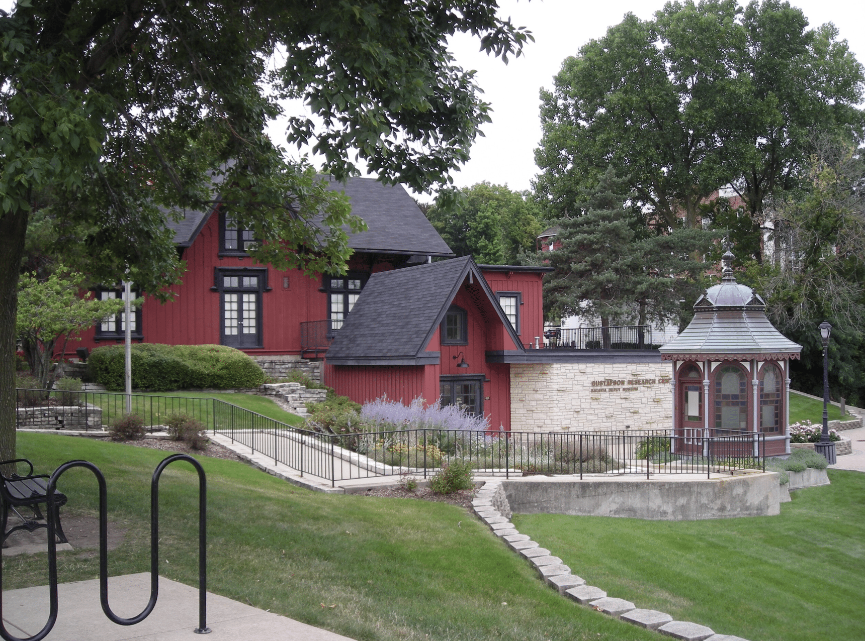 Historic building in Batavia, Illinois, featuring red exterior and stone accents, adjacent gazebo, and landscaped grounds, representing the local community's charm and professional services.
